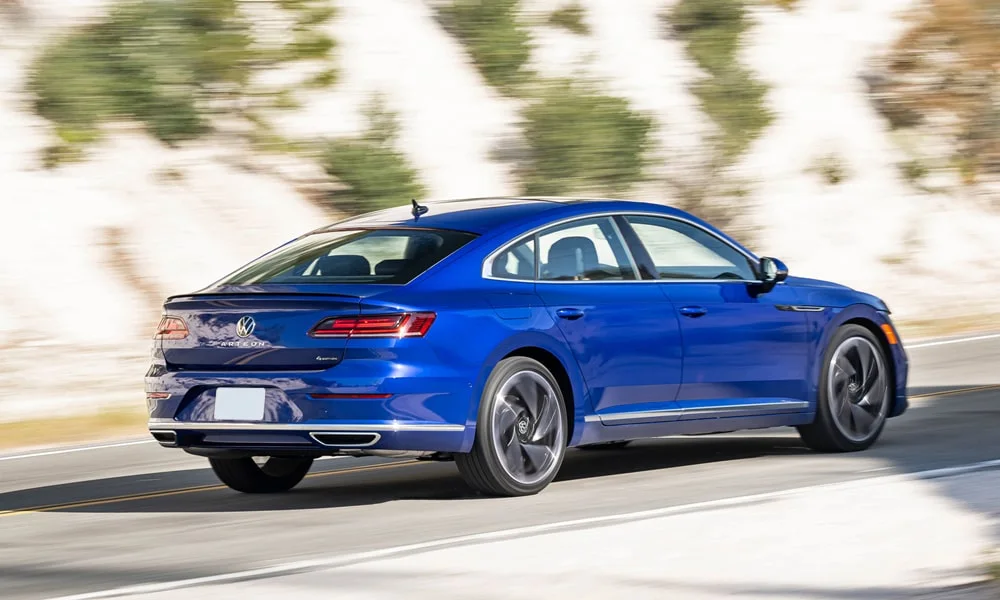 Фото Volkswagen Arteon (2024) — вид сзади, фото 7. Корма в синем цвете: графика фонарей и пластика пятой двери. Светодиодная полоса или раздельные секции — задняя оптика стала главным украшением кормы Volkswagen Arteon (2024) — вид сзади, фото 7