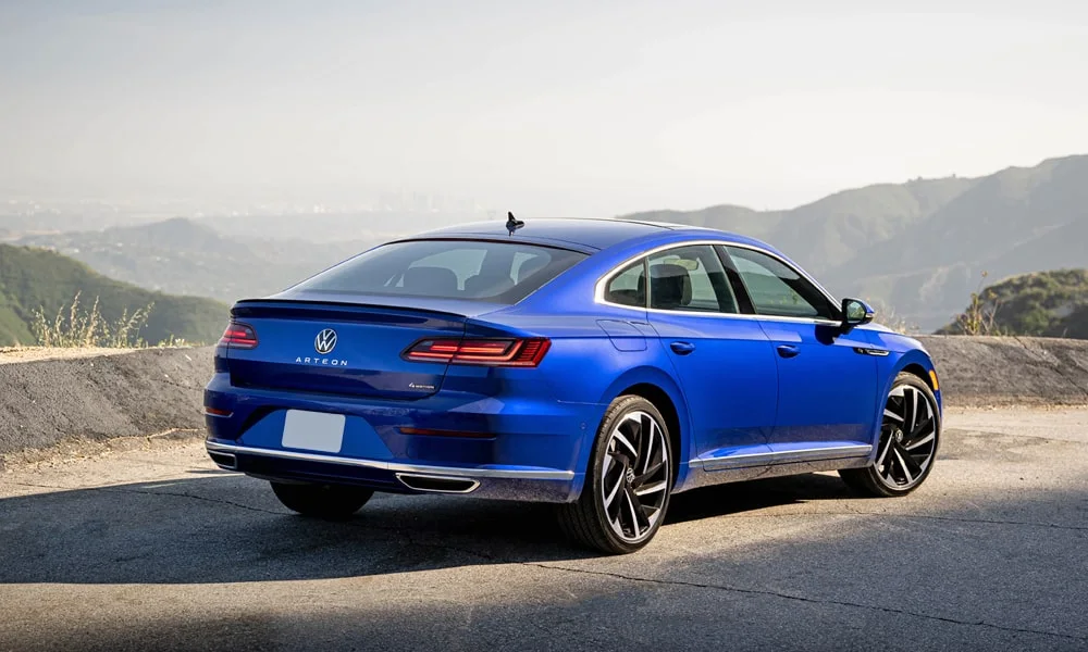 Фото Volkswagen Arteon (2024) — вид сзади, фото 8. Синий кузов сзади — фонари и бампер определяют ночной образ модели. Светодиодная полоса или раздельные секции — задняя оптика стала главным украшением кормы Volkswagen Arteon (2024) — вид сзади, фото 8