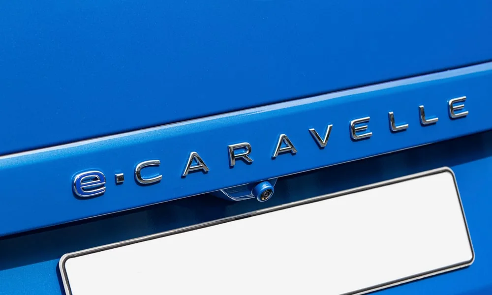 Фото Volkswagen Caravelle (2024) — эмблема. Логотип марки крупным планом. Шильдик версии на корме помогает отличать комплектации Volkswagen Caravelle (2024) — эмблема