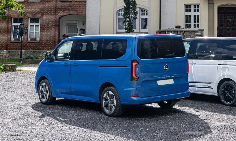 Фото Volkswagen Caravelle (2024) — вид сзади, фото 2. Линия крыши, стойки и задняя дверь в синем исполнении Volkswagen Caravelle (2024) — вид сзади, фото 2