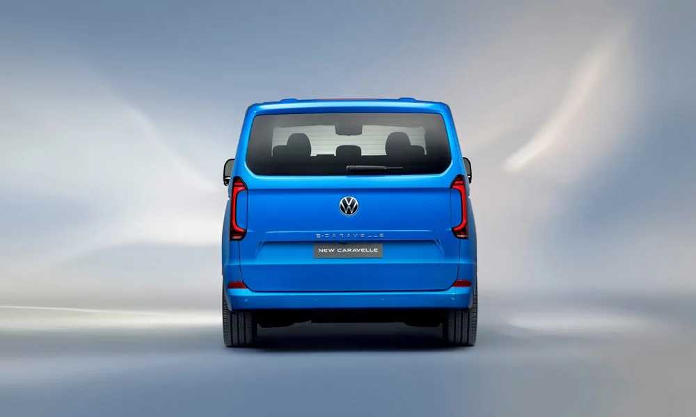 Фото Volkswagen Caravelle (2024) — вид сзади, фото 4. Синий кузов сзади — фонари и бампер определяют ночной образ модели Volkswagen Caravelle (2024) — вид сзади, фото 4