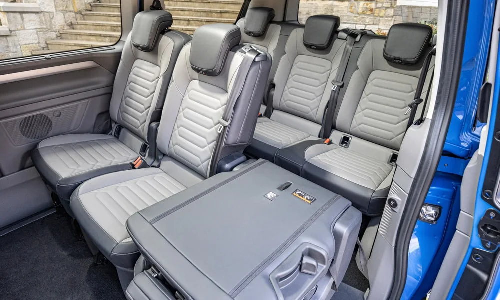Фото Volkswagen Caravelle (2024) — задние сиденья, фото 3. Посадка второго ряда: подголовники и подлокотник. Плоский пол упрощает посадку втроём Volkswagen Caravelle (2024) — задние сиденья, фото 3