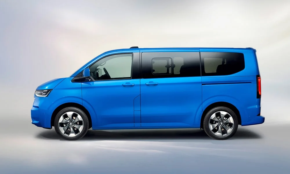 Фото Volkswagen Caravelle (2024) — вид сбоку, фото 2. Сбоку читаются линия остекления и характер выштамповок на синем кузове Volkswagen Caravelle (2024) — вид сбоку, фото 2