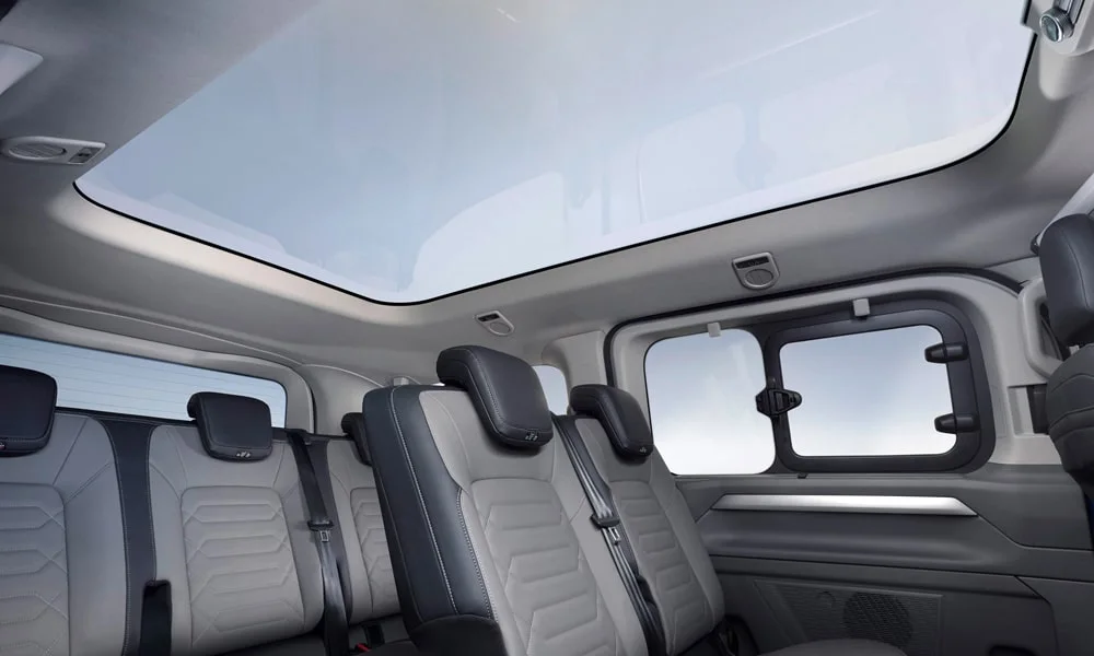 Фото Volkswagen Caravelle (2024) — панорамная крыша. Вид на остекление крыши из салона. Люк с функцией проветривания приподнимается задней кромкой Volkswagen Caravelle (2024) — панорамная крыша