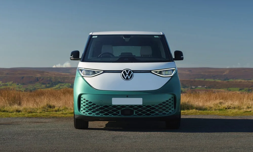 Фото Volkswagen ID Buzz (2024) — вид спереди, фото 11. Зелёный кузов, строгая симметрия оптики — базовый ракурс знакомства с дизайном. Рисунок ходовых огней — подпись модели, по нему её узнают в потоке Volkswagen ID Buzz (2024) — вид спереди, фото 11