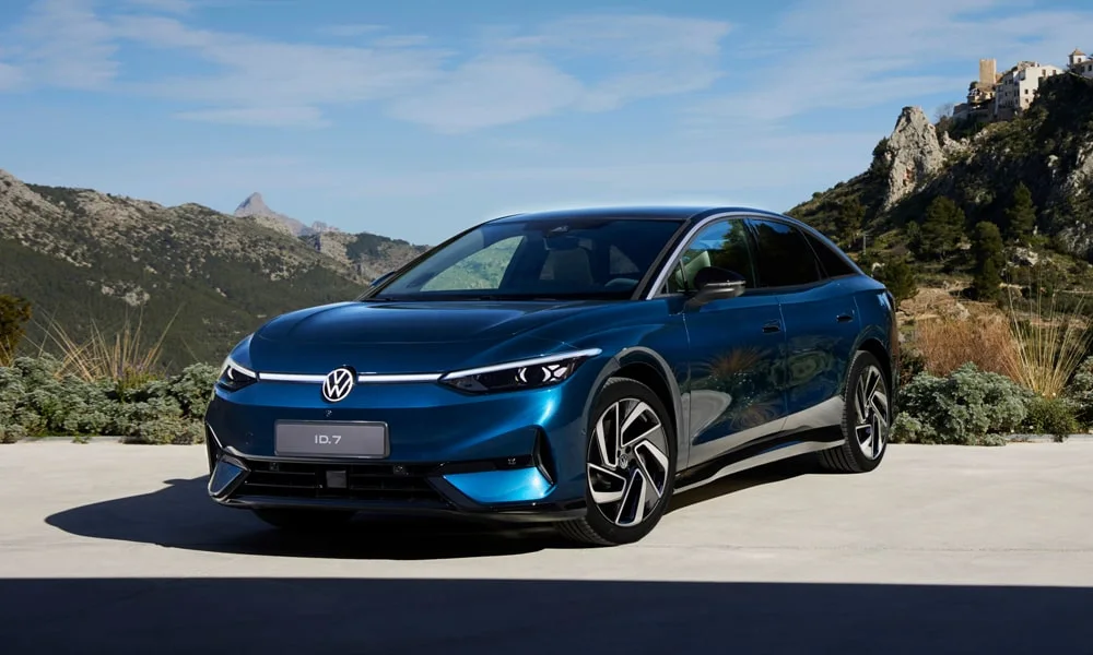 Фото Volkswagen ID 7 (2024) — вид спереди, фото 9. Кузов в синем цвете: рисунок оптики и решётки задаёт узнаваемое «лицо» модели. Дневные ходовые огни включаются автоматически с запуском Volkswagen ID 7 (2024) — вид спереди, фото 9