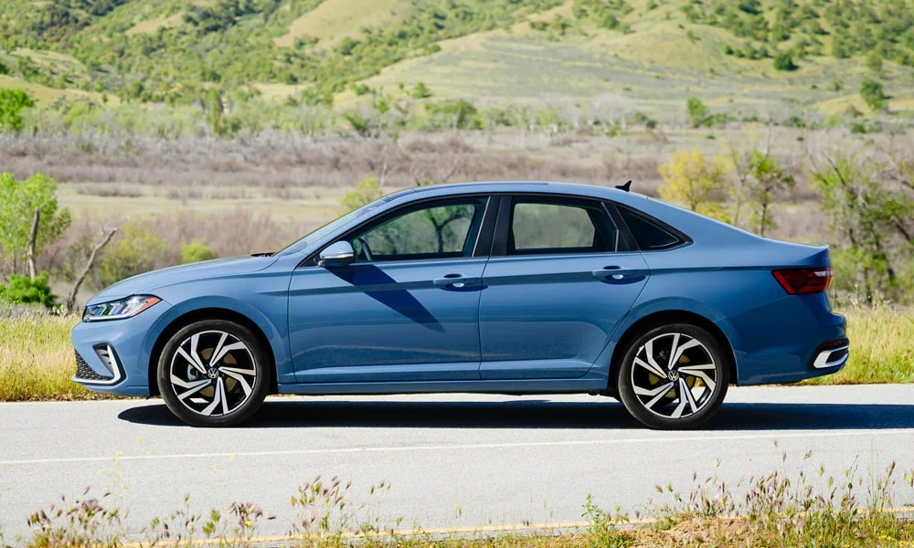 Фото Volkswagen Jetta (2024) — вид сбоку, фото 3. Синий кузов в профиль — пропорции, высота посадки и дизайн дисков. Длинная база — простор второго ряда; короткие свесы упрощают парковку Volkswagen Jetta (2024) — вид сбоку, фото 3