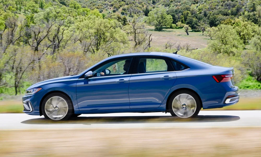 Фото Volkswagen Jetta (2024) — вид сбоку, фото 4. Синий кузов в профиль — пропорции, высота посадки и дизайн дисков Volkswagen Jetta (2024) — вид сбоку, фото 4