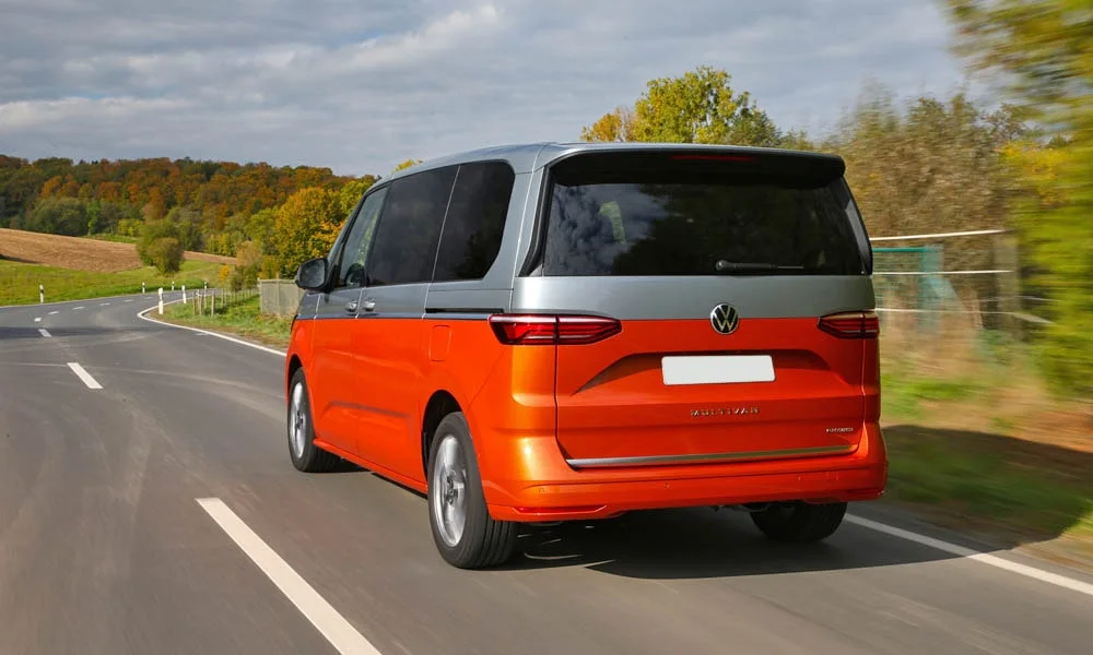 Фото Volkswagen Multivan (2024) — вид сзади, фото 3. Оранжевый кузов сзади — фонари и бампер определяют ночной образ модели. Светодиодная полоса или раздельные секции — задняя оптика стала главным украшением кормы Volkswagen Multivan (2024) — вид сзади, фото 3
