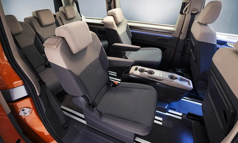 Фото Volkswagen Multivan (2024) — задние сиденья, фото 6. Задний диван в практичной ткани: посадка и центральный подлокотник. Плоский пол упрощает посадку втроём Volkswagen Multivan (2024) — задние сиденья, фото 6