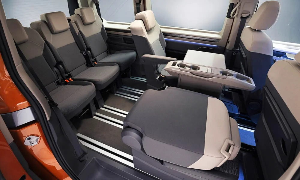 Фото Volkswagen Multivan (2024) — задние сиденья, фото 8. Посадка второго ряда: подголовники и подлокотник. Крепления ISOFIX для детских кресел — в основании спинки Volkswagen Multivan (2024) — задние сиденья, фото 8