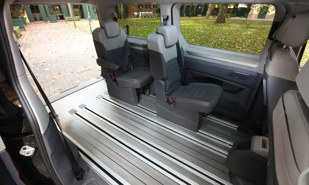Фото Volkswagen Multivan (2024) — задние сиденья, фото 9. Посадка второго ряда: подголовники и подлокотник. Крепления ISOFIX для детских кресел — в основании спинки Volkswagen Multivan (2024) — задние сиденья, фото 9