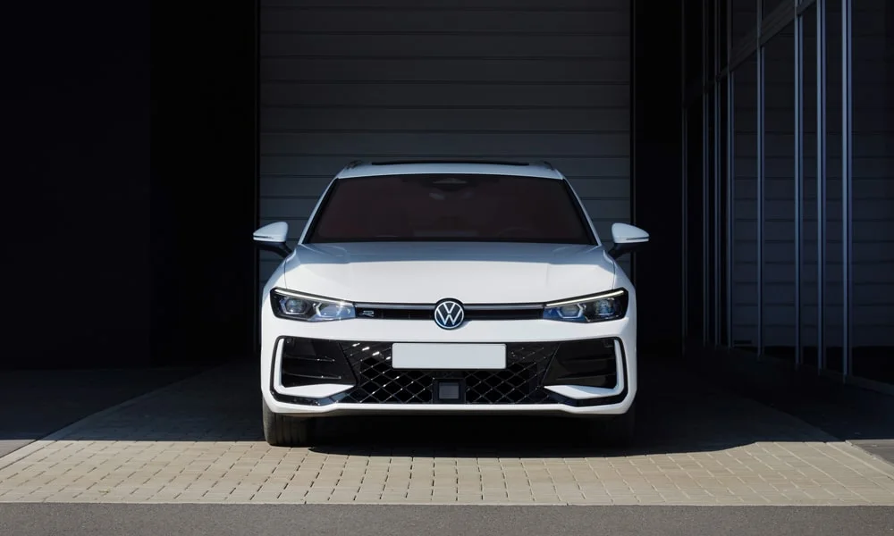 Фото Volkswagen Passat Variant (2024) — вид спереди, фото 7. Кузов в белом цвете: рисунок оптики и решётки задаёт узнаваемое «лицо» модели. Рисунок ходовых огней — подпись модели, по нему её узнают в потоке Volkswagen Passat Variant (2024) — вид спереди, фото 7
