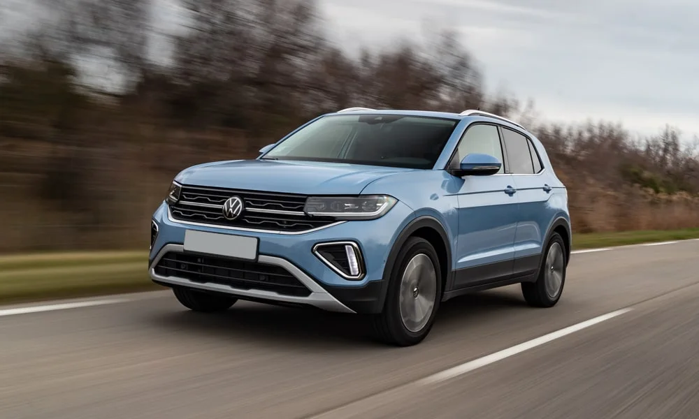 Фото Volkswagen T-Cross — вид спереди, фото 4. Передок в синем исполнении — крупная светотехника и выразительный бампер. Рисунок ходовых огней — подпись модели, по нему её узнают в потоке Volkswagen T-Cross — вид спереди, фото 4