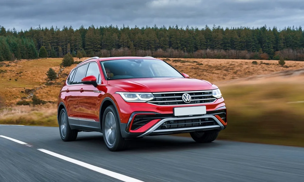 Фото Volkswagen Tiguan Allspace (2024) — вид спереди, фото 4. Кузов в красном цвете: рисунок оптики и решётки задаёт узнаваемое «лицо» модели Volkswagen Tiguan Allspace (2024) — вид спереди, фото 4