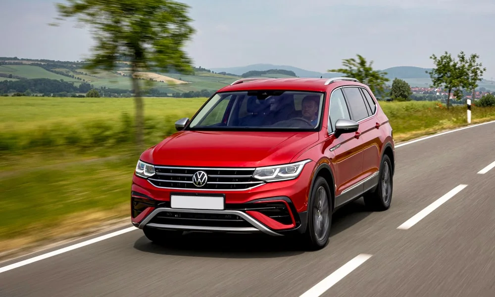 Фото Volkswagen Tiguan Allspace (2024) — вид спереди, фото 7. Красный кузов, строгая симметрия оптики — базовый ракурс знакомства с дизайном. Дневные ходовые огни включаются автоматически с запуском Volkswagen Tiguan Allspace (2024) — вид спереди, фото 7