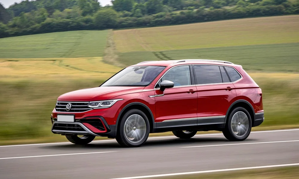 Фото Volkswagen Tiguan Allspace (2024) — вид спереди, фото 10. Кузов в красном цвете: рисунок оптики и решётки задаёт узнаваемое «лицо» модели Volkswagen Tiguan Allspace (2024) — вид спереди, фото 10