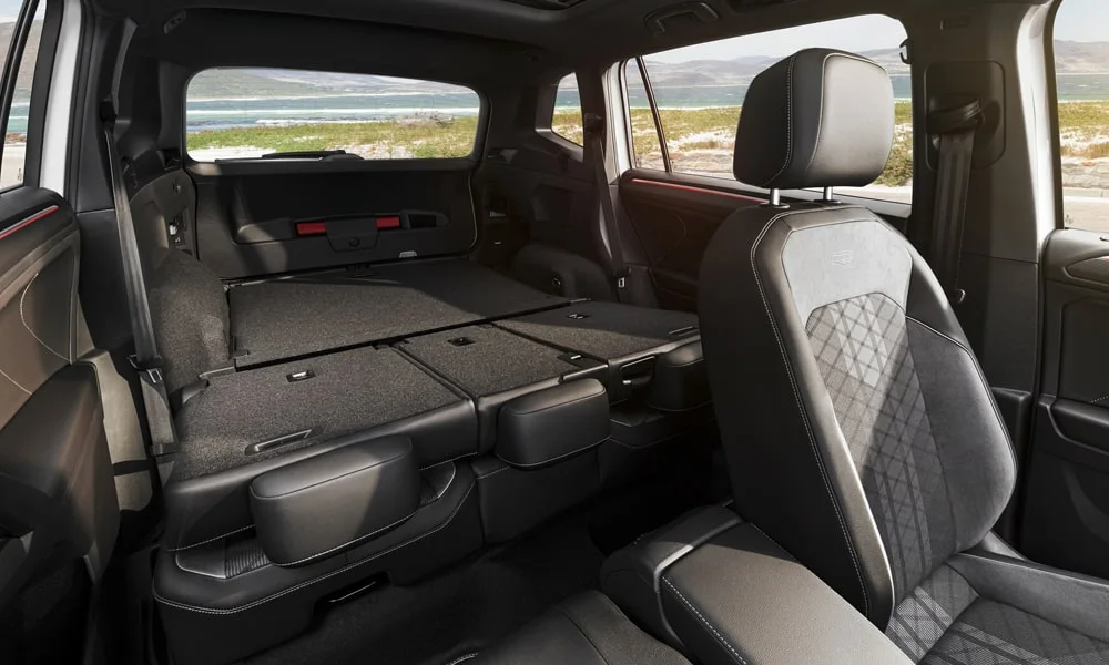 Фото Volkswagen Tiguan Allspace (2024) — багажник. Форма проёма, ровный пол и организация пространства. Электропривод двери с датчиком под бампером — руки заняты, багажник открыт Volkswagen Tiguan Allspace (2024) — багажник