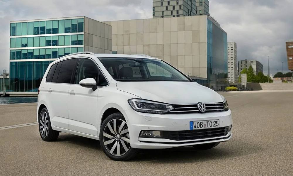 Фото Volkswagen Touran — вид спереди, фото 7. Белый кузов, строгая симметрия оптики — базовый ракурс знакомства с дизайном. Рисунок ходовых огней — подпись модели, по нему её узнают в потоке Volkswagen Touran — вид спереди, фото 7