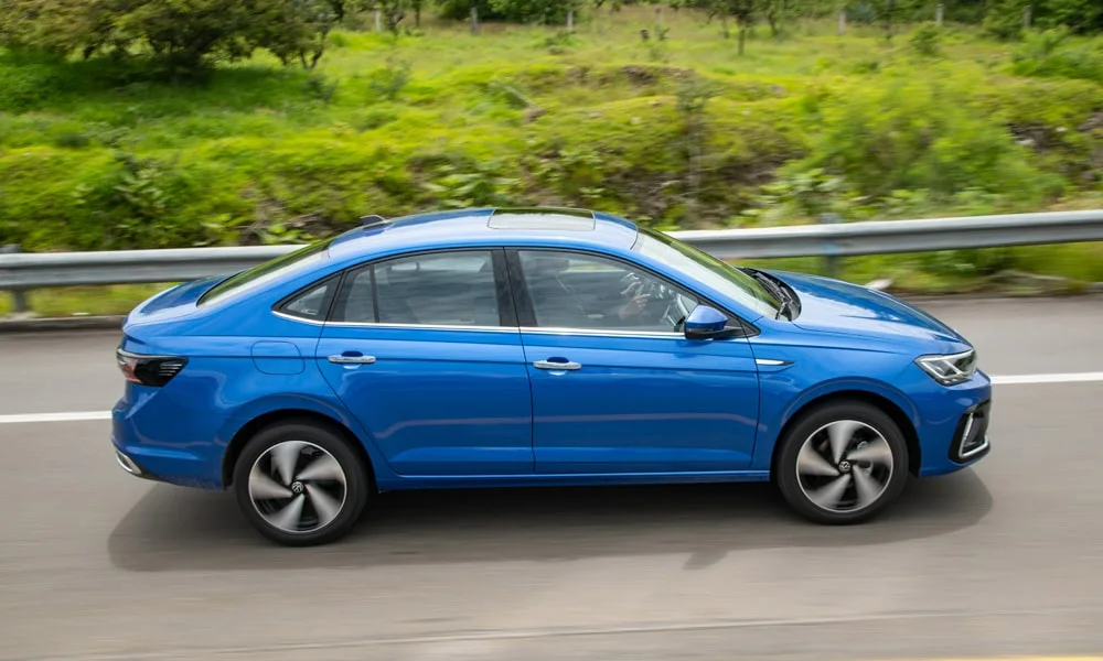 Фото Volkswagen Virtus (2024) — вид сбоку. Профиль в синем цвете: соотношение колёсной базы и свесов. Хромированные или чёрные молдинги окон отличают комплектации Volkswagen Virtus (2024) — вид сбоку