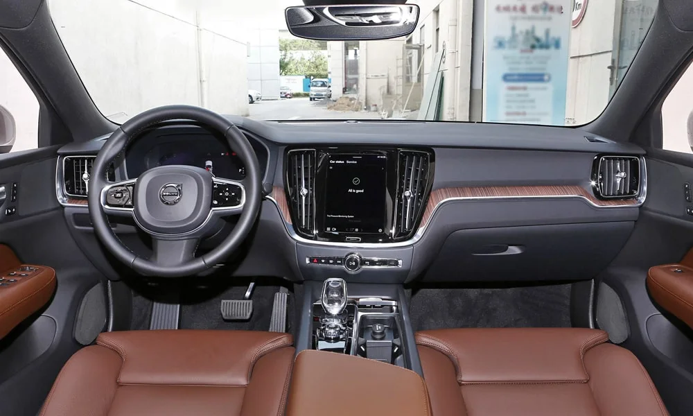 Фото Volvo S60 (2024) — передняя панель. Панель в коричневой отделке — видна компоновка экранов и органов управления. Мягкие материалы верхнего яруса и вставки задают уровень интерьера Volvo S60 (2024) — передняя панель