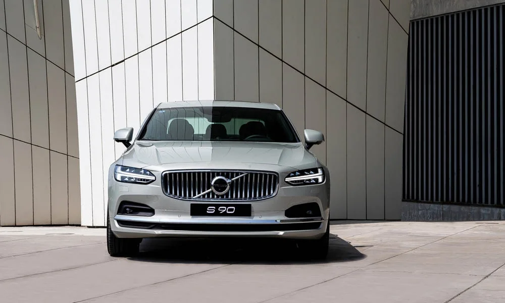 Фото Volvo S90 — вид спереди, фото 9. Серебристый кузов, строгая симметрия оптики — базовый ракурс знакомства с дизайном. Дневные ходовые огни включаются автоматически с запуском Volvo S90 — вид спереди, фото 9