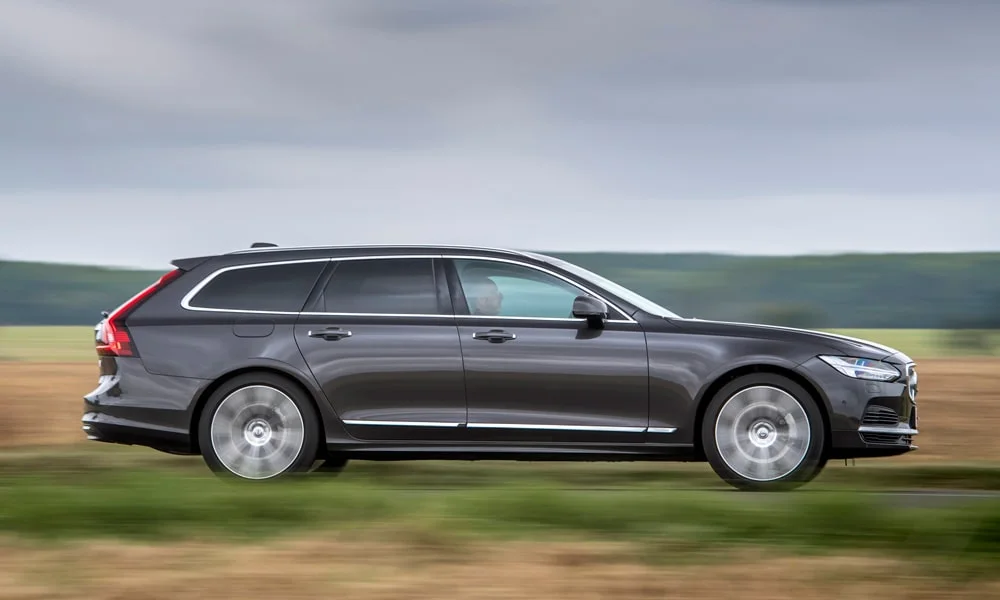 Фото Volvo V90 — вид сбоку, фото 4. Серый кузов в профиль — пропорции, высота посадки и дизайн дисков. Хромированные или чёрные молдинги окон отличают комплектации Volvo V90 — вид сбоку, фото 4
